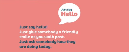 Speech bubble that says "Just Say Hello". Text on a pink background reads: Just Say Hello! JUst give somebody a friendly smile as you walk past. Just ask somebody how they are doing today.