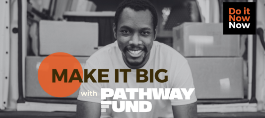Black and white photograph of a man smiling. Background is the back of a van full of boxes.  Text reads "Make it big with Pathway fund" in a black box in the top right hand corner, it reads "Do it now now"