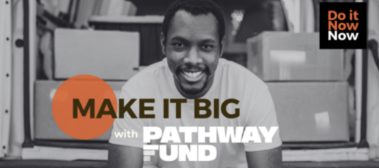 Black and white photograph of a man smiling. Background is the back of a van full of boxes.  Text reads "Make it big with Pathway fund" in a black box in the top right hand corner, it reads "Do it now now"